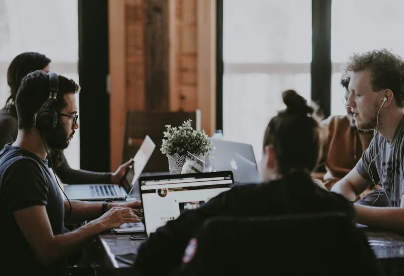 Équipe au travail autour d'une grande table avec des ordinateurs portables