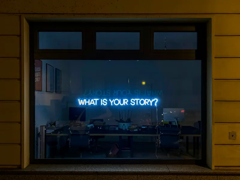 Néon bleu « What is your story? » dans une vitrine de nuit