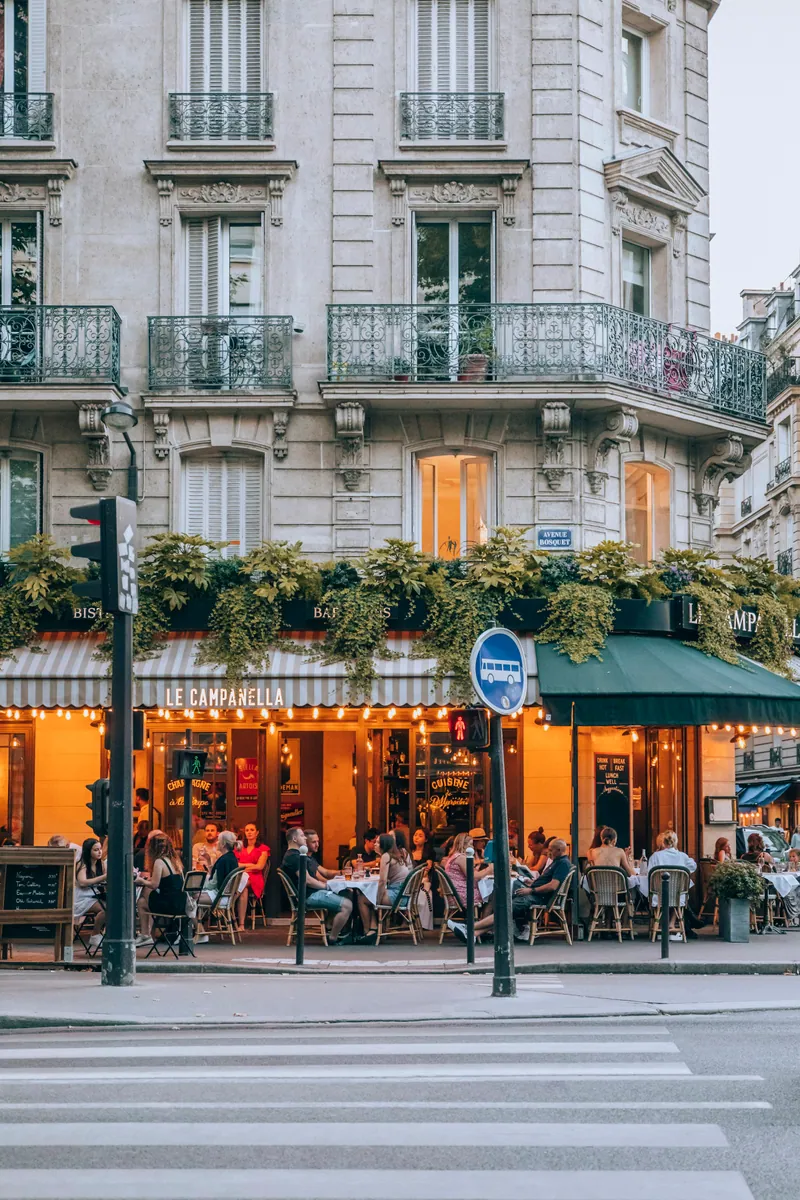 Terrasse de café animée au pied d'un immeuble haussmannien à Paris