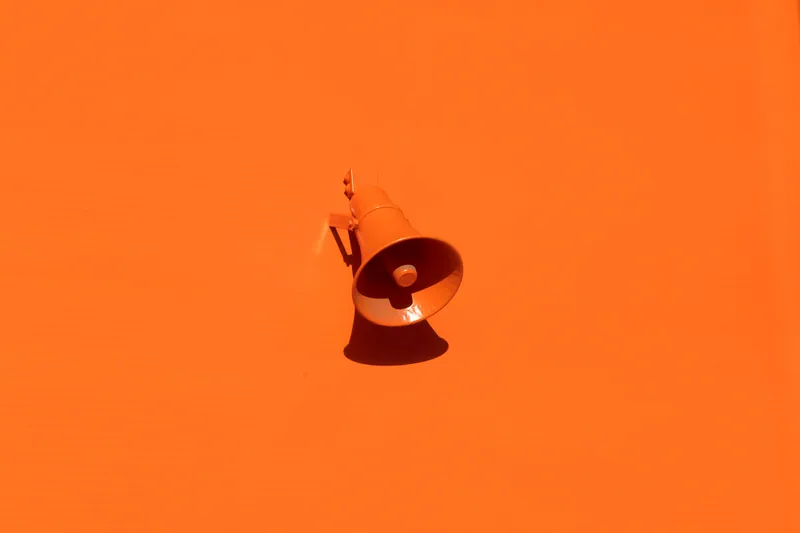 Mégaphone orange fixé sur un mur orange