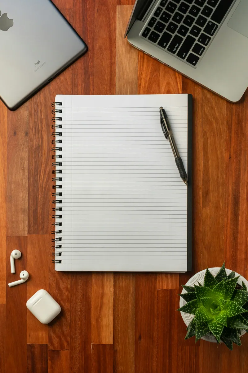 Carnet à spirale vierge et stylos sur un bureau noir