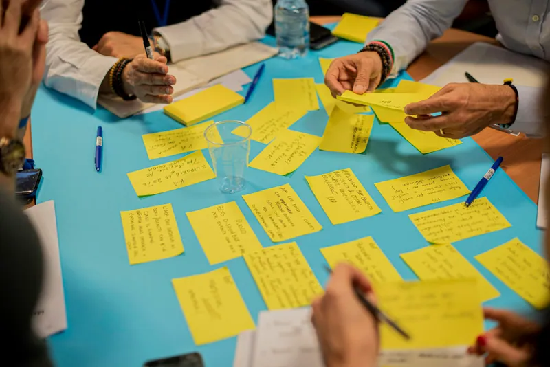 Mains organisant des post-it jaunes sur une table bleue