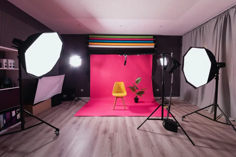 Studio photo avec un fond rose et une chaise jaune