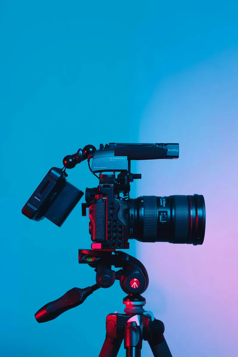 Caméra avec microphone sur trépied devant un fond bleu