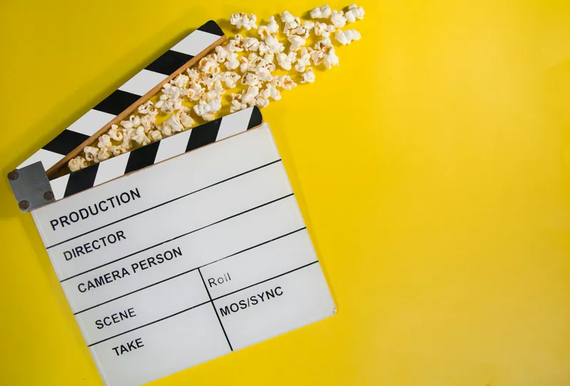 Clap de cinéma et pop-corn sur un fond jaune