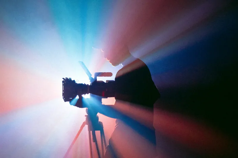 Silhouette d'un cadreur filmant dans une lumière bleue et rouge
